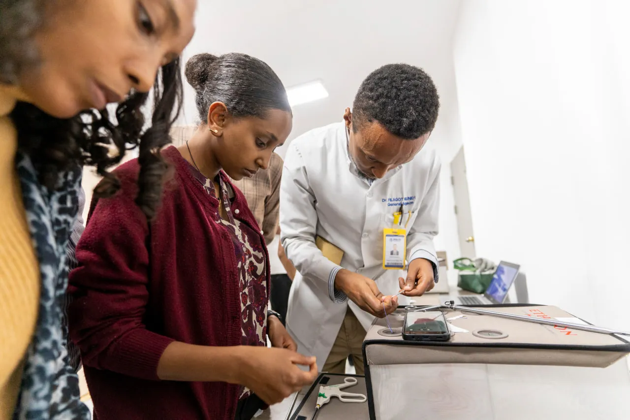 A trainee practises on a laparoscopic simulator with a trainer